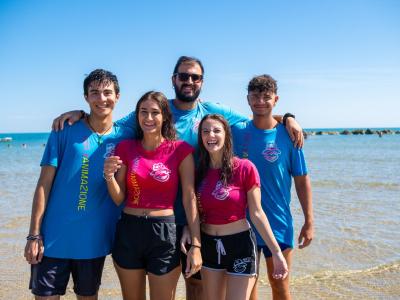 Groupe d'amis souriants à la plage avec des t-shirts colorés.