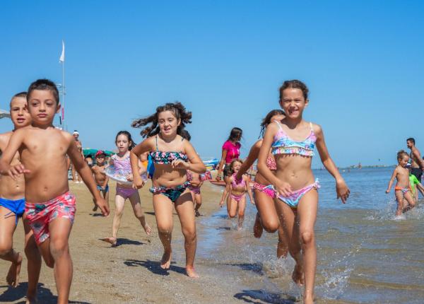 Enfants courant joyeusement sur la plage par une journée d'été.