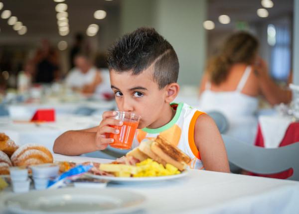 Enfant boit du jus au petit-déjeuner dans un restaurant.