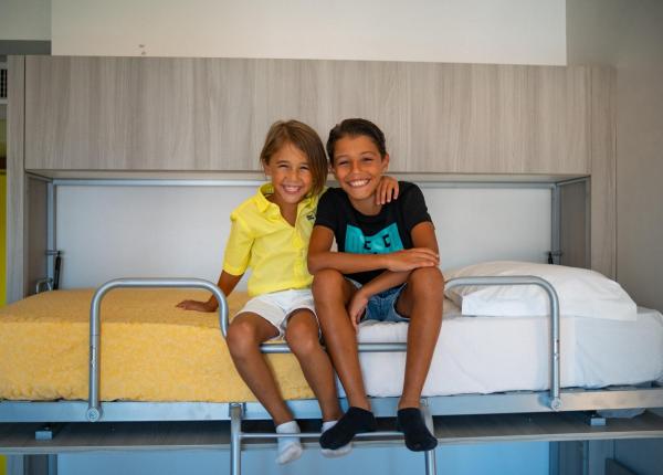 Deux enfants souriants assis sur un lit superposé.
