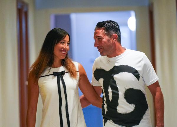 Coppia sorridente cammina insieme in un corridoio.