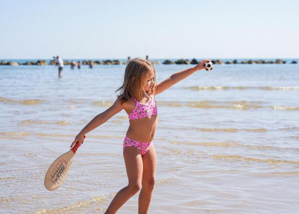 Fille joue au beach tennis sous le soleil.